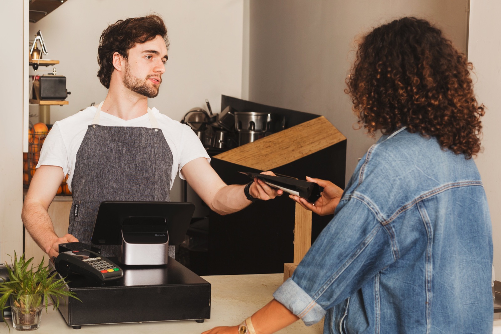 Customer tapping a card to pay at a café counter